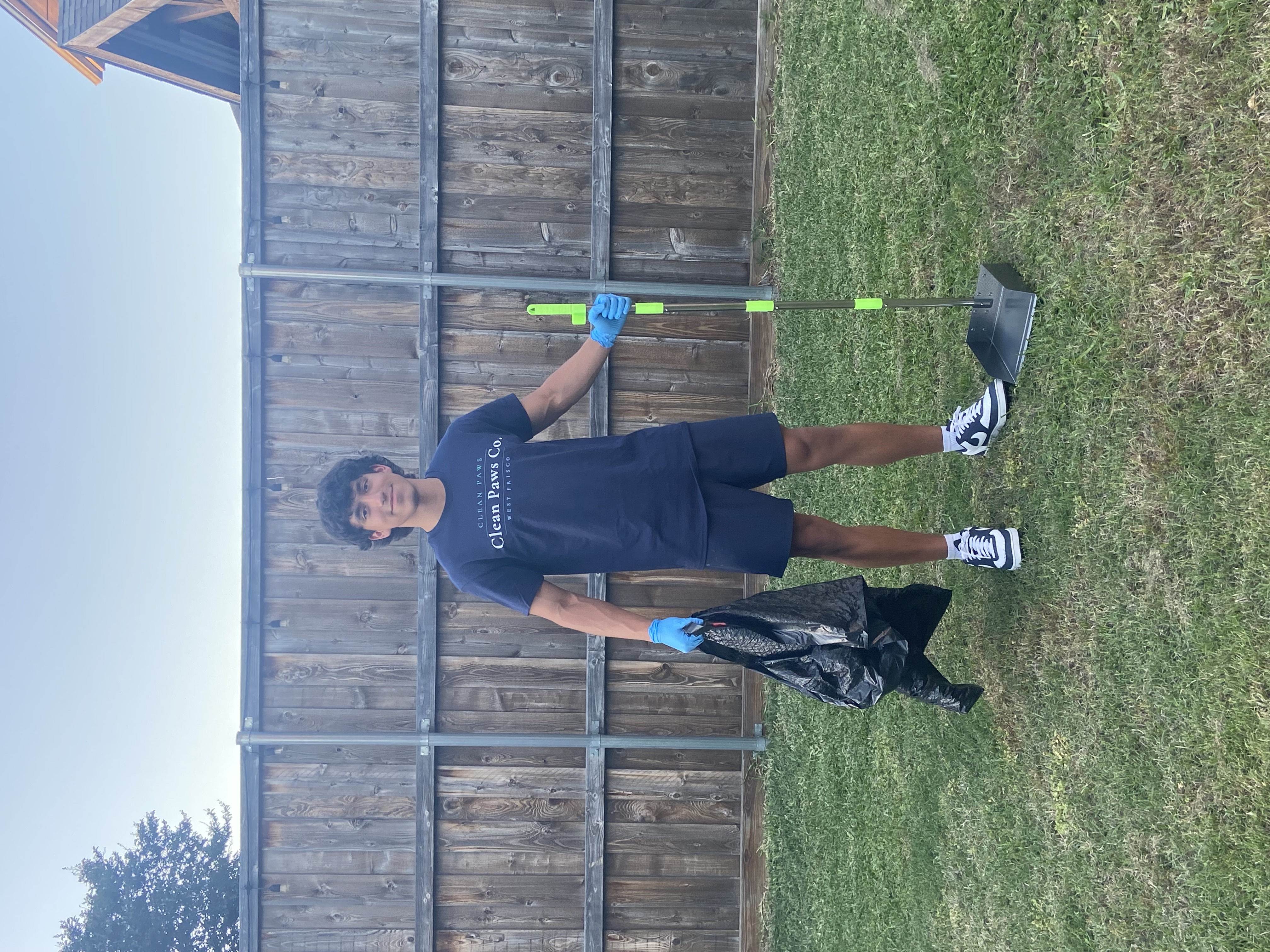 Oscar, founder of Clean Paws Co., holding equipment in a clean West Frisco backyard